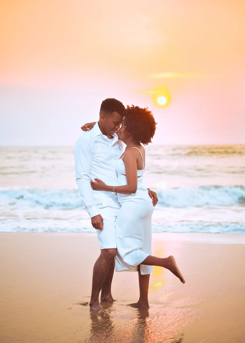 Casal abraçado na praia com o sol ao fundo